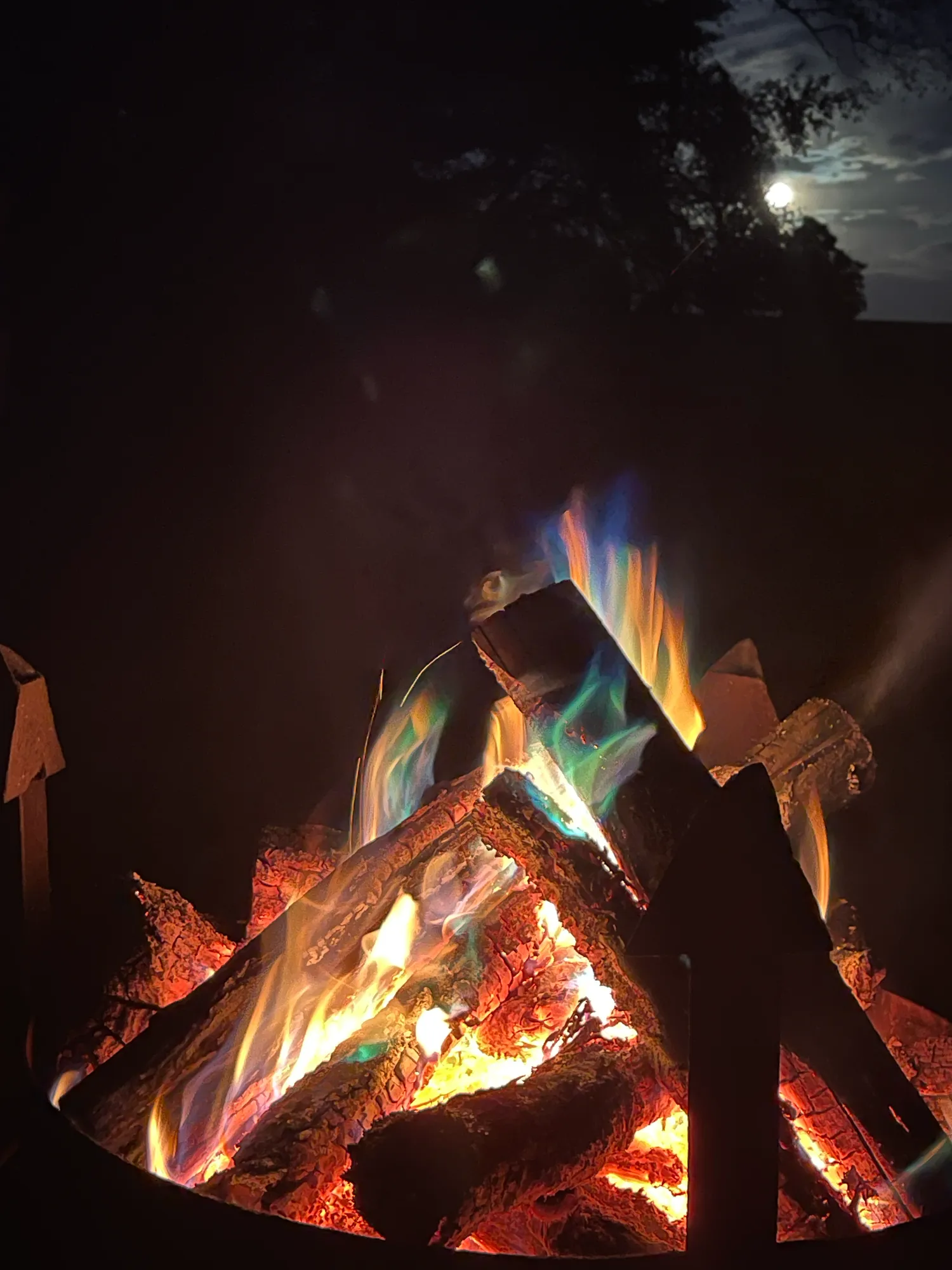 Evening campfire with colorful flames under a full moon